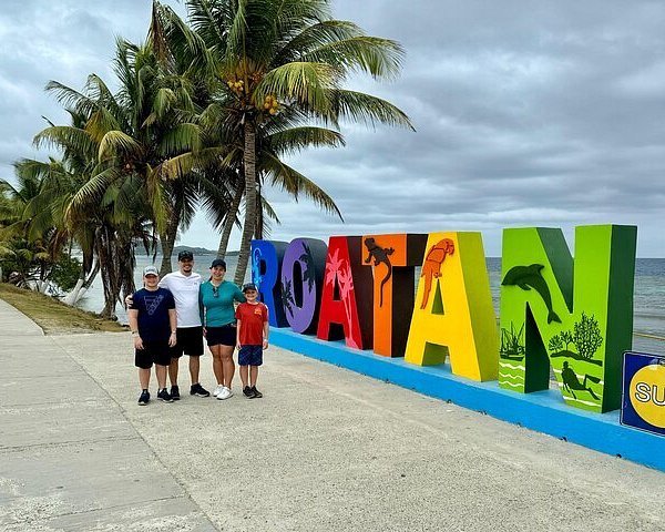 Familia frente al letrero de Roatán